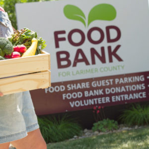 Woman holding a box of fresh produce outside the Larimer County Food Bank