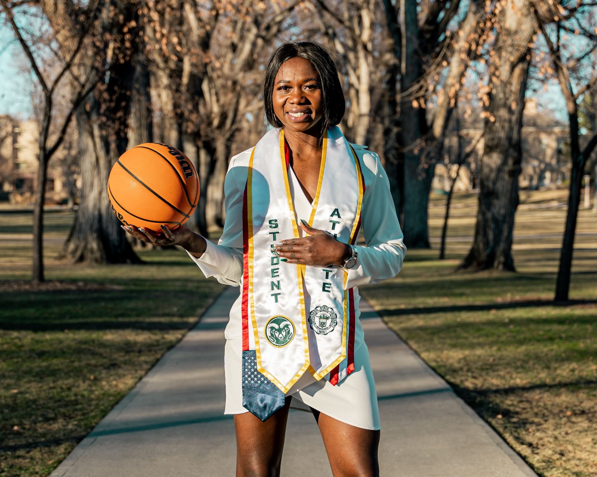 Upe Atosu posing on the oval in her regalia, basketball in hand