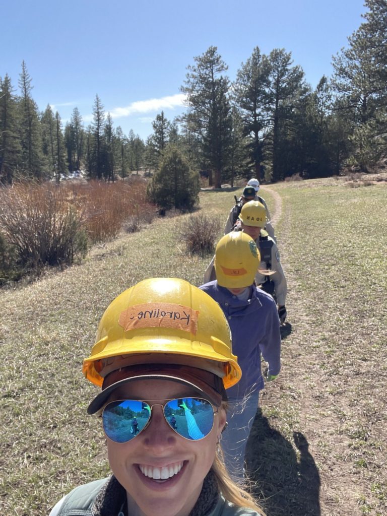 Students with hardhats walking on a trail single-file