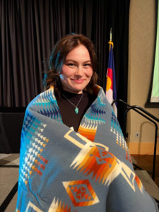 Zoe Mireles wrapped in a blanked with traditional Indigenous Native American pattern
