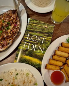 Photo of Joel Delgado's ('14) zine, "Lost Eden," surrounded by traditional food -- egg rolls, rice, fish
