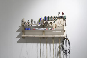 A shelf against a white wall containing electrical and sound equipment.